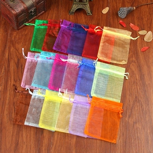 Flat lay of colorful semi-transparent organza drawstring gift bags on a wooden surface