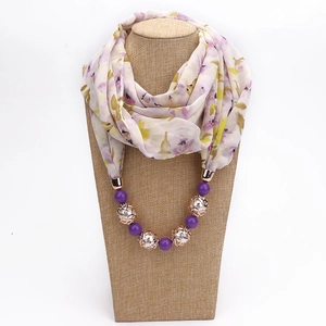 Detailed close-up of floral chiffon scarf necklace with purple and gold beads on a mannequin