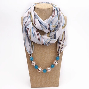 Detailed view of chiffon scarf necklace with feather print and blue beaded jewelry detail