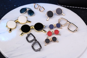 Macro shot of assorted enamel sunglass brooches for suits on a white marble display tray