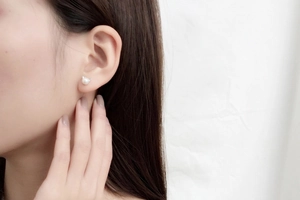 Close-up of elegant pearl cat ear stud earrings worn by a model in a minimal style
