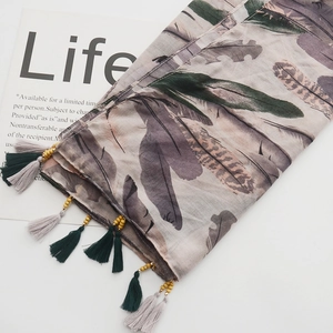 Detailed close-up of bohemian linen scarf with feather print and wooden bead tassels