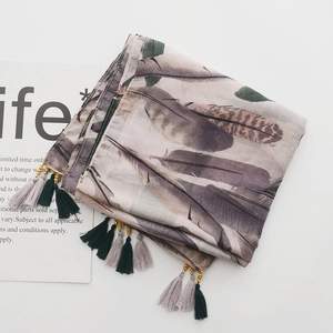 Detail of feather print scarf with decorative tassels and small golden wooden beads