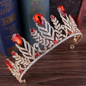 Macro detail of Baroque gold crown with red crystals and rhinestones on wood