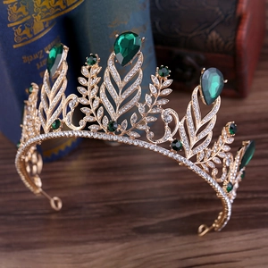 Detail of golden baroque crown with emerald teardrop stones and sparkling crystals