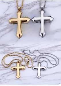 Close-up of gold and silver stainless steel cross pendants with twist chains on marble