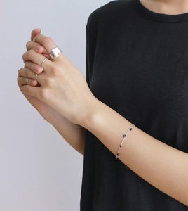 Close-up of minimalist brushed silver wide ring and delicate beaded chain bracelet set