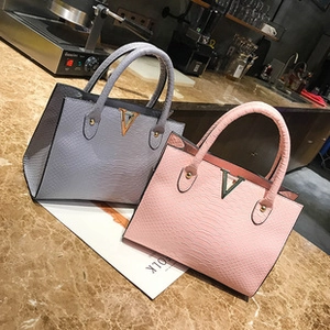 Detail of pink and grey faux snakeskin mini bags with golden V-shaped metal accents