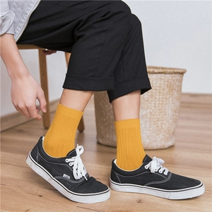 Close-up of bright yellow ribbed cotton socks for men worn on light wood flooring