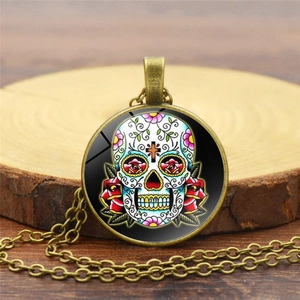 Mexican sugar skull glass gem pendant necklace with bronze chain on a wooden base