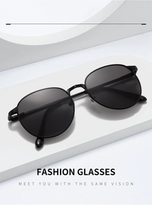 Detail of vintage oval metal sunglasses featuring intricate floral engraving on temples