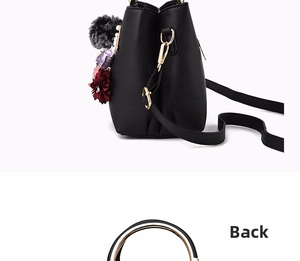 Detail view of black lychee leather bucket bag with metal ring handle and gray pompom charm