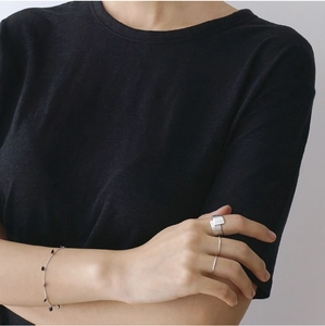 Close-up of a minimalist brushed silver geometric ring and beaded chain bracelet on hand