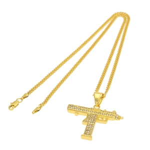 Vue détaillée du pendentif pistolet doré serti de strass brillants sur fond blanc