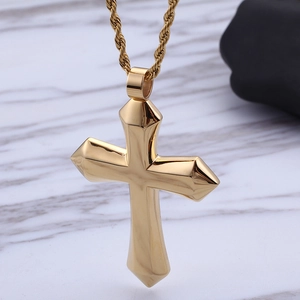 Polished gold stainless steel cross pendant necklace with twisted rope chain on marble