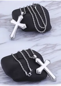 Detailed side view of a large polished stainless steel cross pendant on a spiral chain