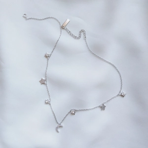 Elegant 925 sterling silver necklace featuring sparkling star and moon pendants on white silk