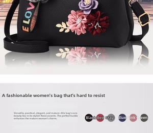 Detail of black pebbled leather crossbody bag with 3D floral accents and LOVE strap