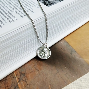 Detail of vintage sterling silver guardian angel embossed pendant on a ball chain