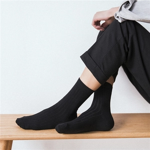 Detail of black ribbed cotton mid-calf socks showing soft elastic texture on model