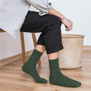 Dark green cotton ribbed crew socks for men shown in a cozy home setting with natural light