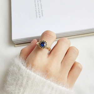 Vintage gold ring with sapphire blue center stone and black accents on a hand
