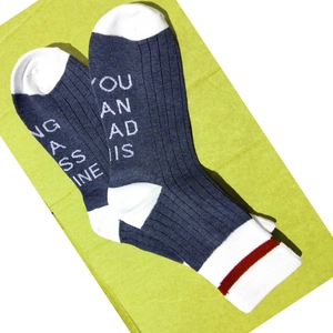Detail of navy knit socks featuring funny printed text on the soles and striped cuffs