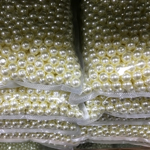 Detailed view of bulk ivory ABS faux pearls with pre-drilled holes for DIY jewelry