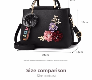 Detail of floral accents and plush LOVE charm on black litchi pattern leather handbag