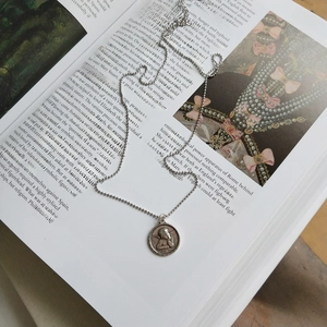 Detailed view of vintage guardian angel relief on silver bead chain over an open book