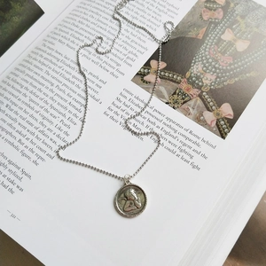Artistic display of 925 silver angel pendant necklace on a classic vintage book page