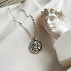 Macro shot of 925 sterling silver guardian angel relief pendant with woven texture frame