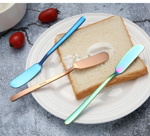 Detail of long handle 304 stainless steel butter knives in rose gold and blue on a plate