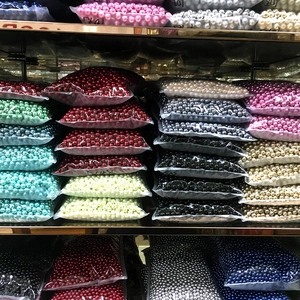 Assorted colors of ABS faux pearls in transparent bags on storage shelves for DIY jewelry