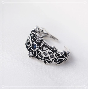 Macro detail of vintage S925 silver ring featuring blue gemstone and lace pattern engraving