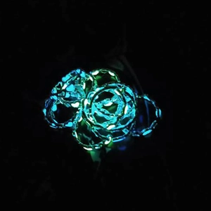 Detailed macro view of glow-in-the-dark rose shaped ring with neon luminous light effects