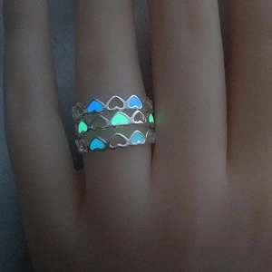 Close-up of hollow heart glow-in-the-dark rings with blue and green luminous effect