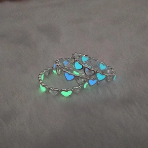 Close-up of three luminous hollow heart rings glowing in blue and green light