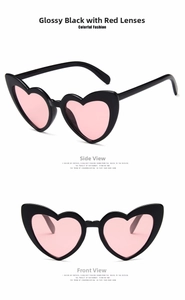Detail view of heart-shaped sunglasses featuring black frames and pink tinted lenses