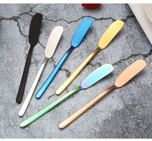 Set of six stainless steel butter knives in various colors on grey marble background