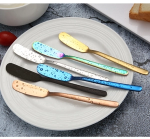 Detailed close-up of colorful 304 stainless steel butter knives set on a white ceramic plate