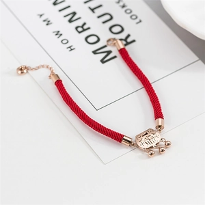 Detailed shot of red woven bracelet with rose gold hollow fortune charm and bells