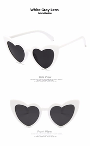 Detail view of heart-shaped white sunglasses with dark grey lenses in front and side angles