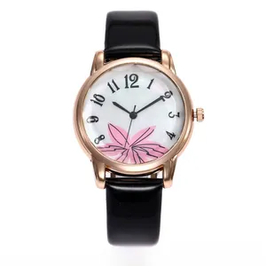 Detail of rose gold watch case with floral dial and black patent leather strap