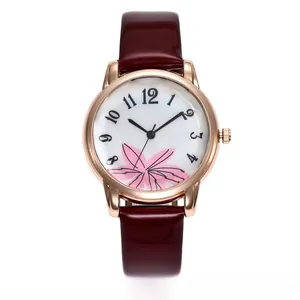 Detailed close-up of a women's rose gold watch with a floral dial and burgundy leather strap
