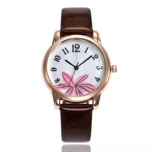 Close-up of rose gold watch with pink floral dial and brown leather strap details