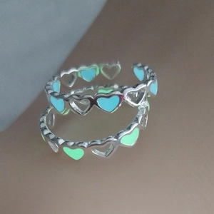 Macro view of two adjustable hollow heart rings with luminous green and blue enamel detail