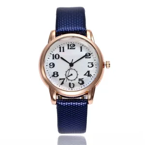 Detail of rose gold watch case with white dial and navy blue embossed honeycomb leather strap