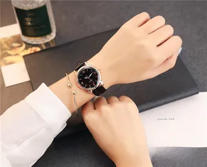 Detail of minimalist women's black leather watch paired with a rose gold bracelet