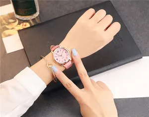 Close-up of a pink leather strap watch and gold knot bracelet on a woman's wrist